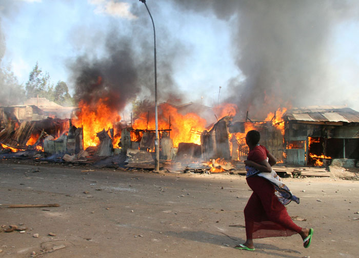 Pregnant woman : A pregnant woman runs past burning shacks in Nairobi's Mathare slum during post-election violence. © Julius Mwelu