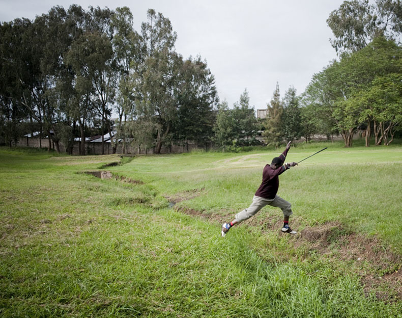 Ousmane jump over water during his weekly golf course in Nairobi Golf Club. Due to teh city expansion, the golf course is surrounded by slum habitations that can be seen in the back © Joan Bardeletti
