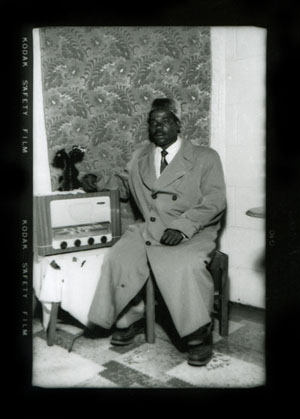 Homme avec manteau d'hiver et poste de radio. Ronald Ngilime, vers 1950.