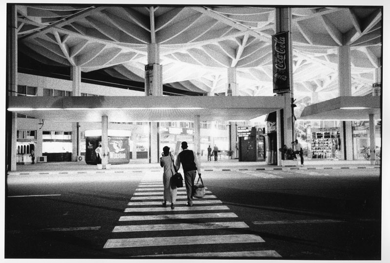 Hadija accompagne Max à l'aéroport International de Dar Es Salaam. Il part rejoindre un oncle aux Etats-Unis qui lui propose un job dans l'hôtellerie. Pour un mois, pour un an, pour la vie.... © Frederic NOY