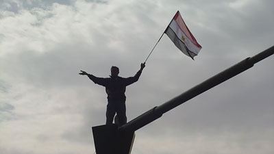 Un révolutionnaire sur la tête d’un char, tenant le drapeau égyptien d’une main, et l’autre lancée en l’air comme s’il s’adressait à un auditoire, tel Cicéron. © Salah Hashem