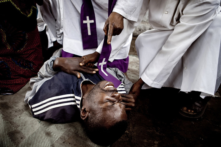 A man is exorcised in a church in Kinshasa after a child witch supposedly cursed him.  © Gwenn Dubourthoumieu