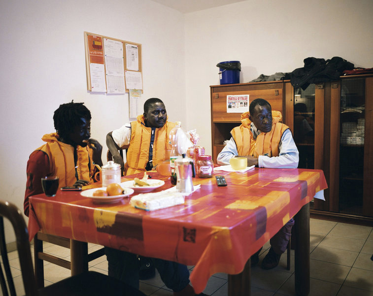 Three Senegalese refugee are having afternoon tea and wtaching Italian Calcio on TV after having done work type activities outside © Joan Bardeletti