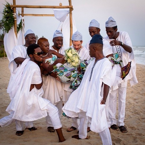 Une jeune mariée est portée par les hommes du marié pendant qu'il regarde, sur les plages de Kokrobite, là où la cérémonie a eu lieu. Le couple a décidé de faire le non-conventionnel en portant Vlisco et batakari au lieu de la robe blanche typique et costume noir. Photo de Nana Kofi Acquah  posté le 30 OCTOBRE 2013